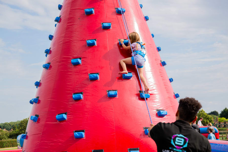 A kid climbing an inflatable wall in a party